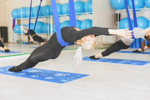 Mujeres jóvenes haciendo ejercicio de yoga aéreo o yoga antigravedad —  Fotos de Stock