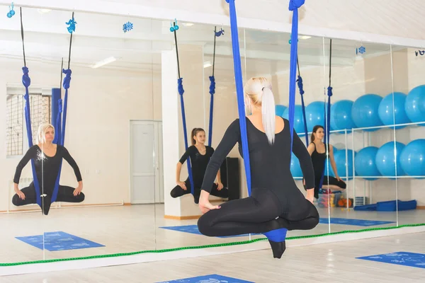 Young women doing aerial yoga exercise or antigravity yoga