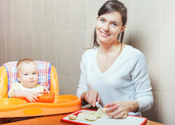 Mom cooking and feeds the baby fruits and vegetables — Stock Image Mom cooking and feeds the baby fruits and vegetables Stock Image