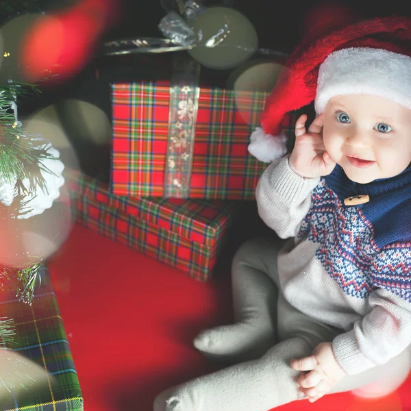 Cutte baby guarda la telecamera, la notte di Cristmas. Cappello Babbo Natale vestito . — Foto Stock