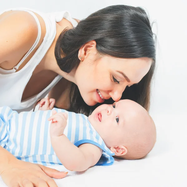 Mãe feliz segurando um menino no fundo branco — Fotografia de Stock