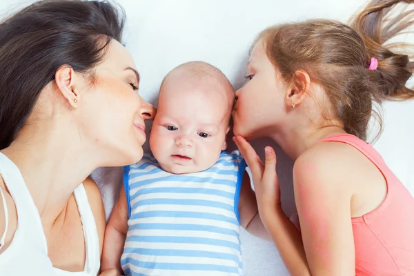 Gelukkige familie moeder met dochter kussen baby — Stockfoto