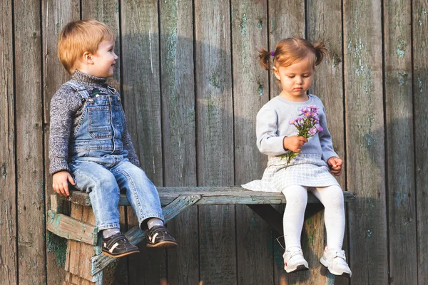 Crianças felizes ao ar livre na temporada de outono, sentadas no banco. Primeiro encontro — Fotografia de Stock
