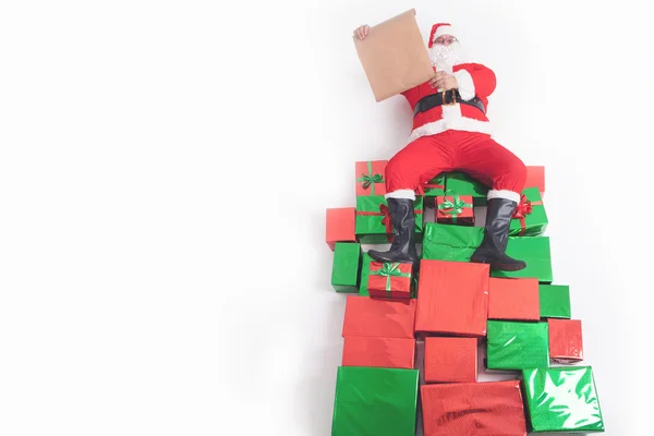 Santa sentado en grandes cajas de regalo y lectura lista de deseos —  Fotos de Stock
