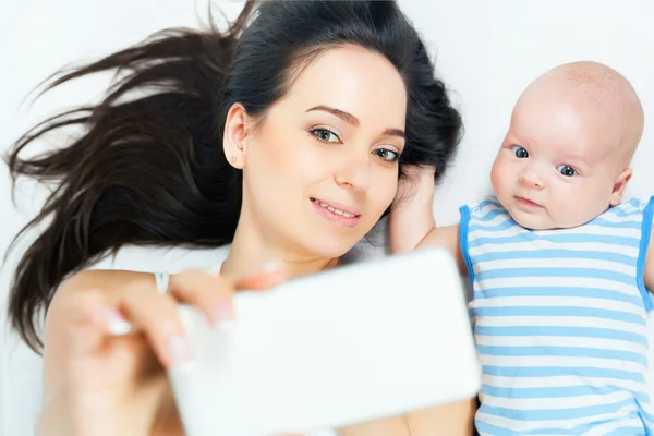 Grappige baby en moeder maken selfie op mobiele telefoon — Stockfoto