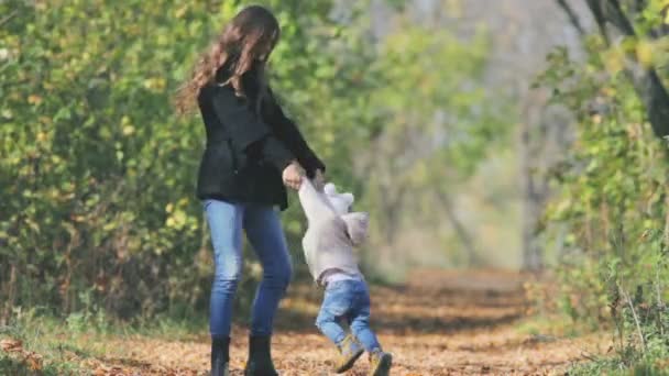Мама выводит ребенка на улицу. Осенние листья фона. Счастливые семейные ценности — стоковое видео