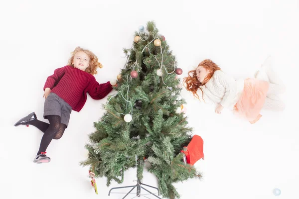 Flying girls decorating Christmas tree, dressed in sweater