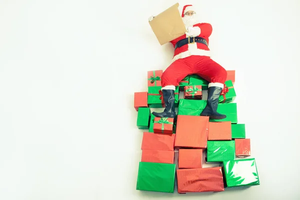 Santa sentado en grandes cajas de regalo y lectura lista de deseos —  Fotos de Stock