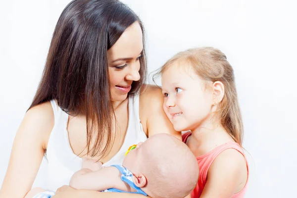 Lycklig familj av mor med dotter tittar på baby — Stockfoto