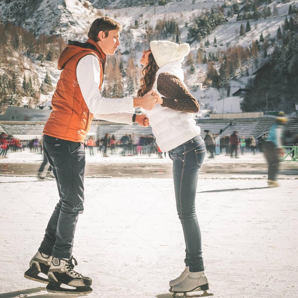 Happy couple, girls and boy ice skating outdoor at rink