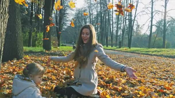 Mère avec bébé jouant des feuilles en plein air. Forêt d'automne, parc .