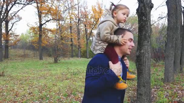 Pai engraçado e bebê sentado no pescoço, jogando ao ar livre . — Vídeo de Stock