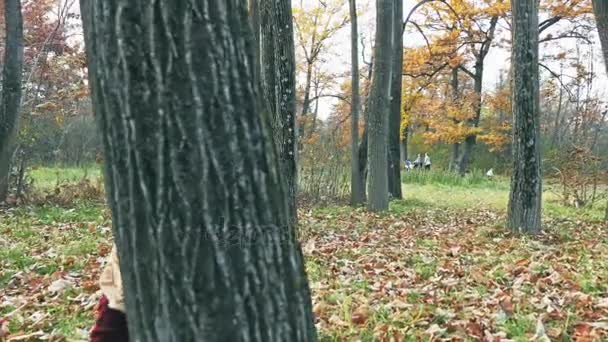 Moeder met baby spelen verstoppertje outdoor, kijkend door de bomen — Stockvideo