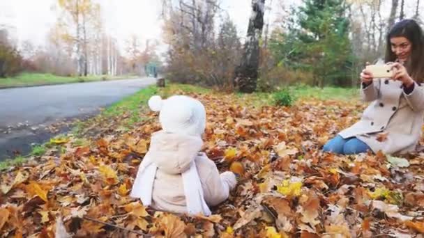 Mãe faz filmagens de bebê no parque de outono, telefone celular — Vídeo de Stock