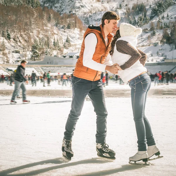 Kussend paar, meisjes en jongen schaatsen buiten op ijsbaan — Stockfoto