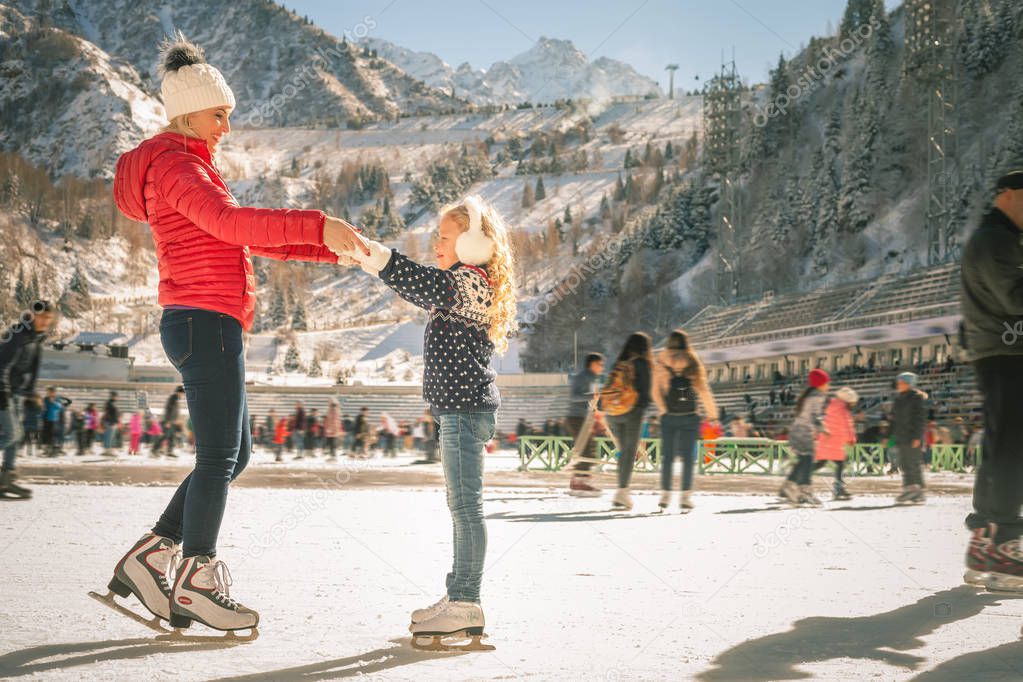 Happy family outdoor ice skating at rink. Winter activities