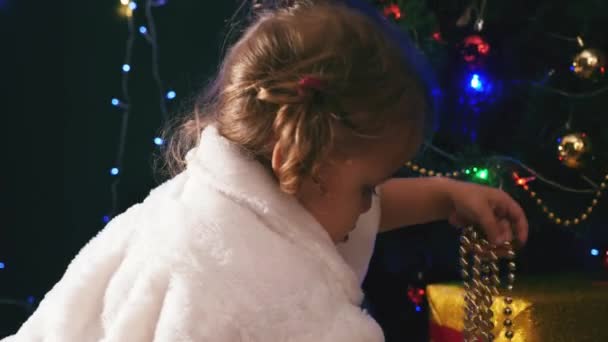 Niedliches Mädchen spielt in der Nähe von ireplace, geschmückter Weihnachtsbaum — Stockvideo