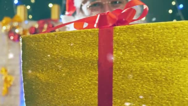 Santa Claus houden een gouden geschenkdoos met rood lint — Stockvideo