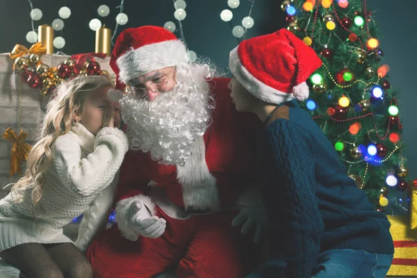 Santa και τα παιδιά γύρω από το στολισμένο χριστουγεννιάτικο δέντρο. Λίστα ευχές — Φωτογραφία Αρχείου