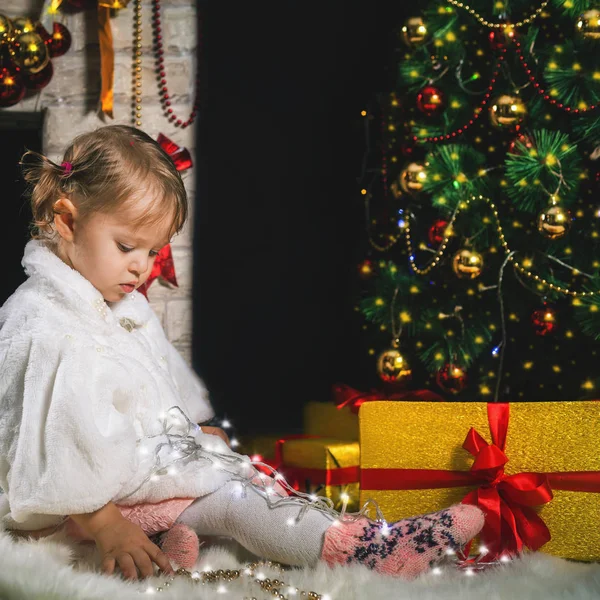 Ragazza carina giocando vicino al camino e decorato albero di Natale — Foto Stock