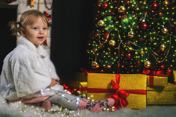 Ragazza carina giocando vicino al camino e decorato albero di Natale — Foto Stock
