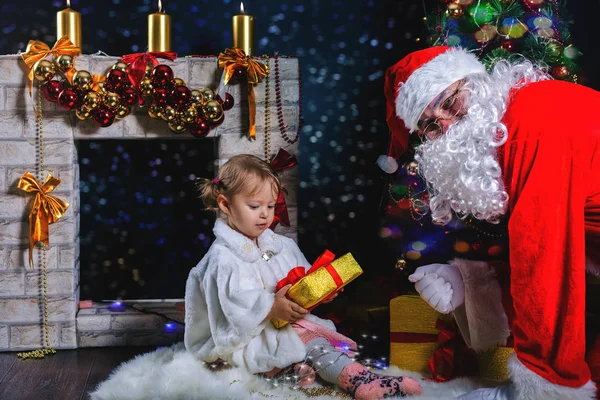 Babbo Natale e ragazza che gioca vicino al camino, albero di Natale decorato — Foto Stock