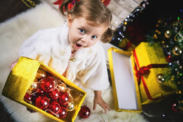 Χαριτωμένο μικρό παιδί κορίτσι διακόσμησης ενός χριστουγεννιάτικου δέντρου. Κόκκινες μπάλες. — Φωτογραφία Αρχείου