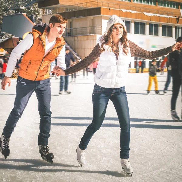 Счастливая пара, девочки и мальчик катаются на коньках на открытом воздухе на катке — стоковое фото