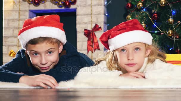 Menino e menina deitados no chão perto da árvore de Natal — Vídeo de Stock