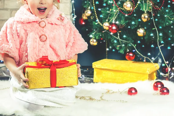 Menina bonito receber um presente perto de decorar árvore de Natal . — Fotografia de Stock