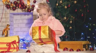 Sevimli küçük kız/açma hediye kutusu, süslü Noel ağacı yakınındaki