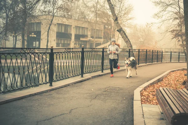 Imagen de una jovencita corriendo con su perro, Alaska Malamute —  Fotos de Stock