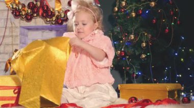 Sevimli küçük kız/açma hediye kutusu, süslü Noel ağacı yakınındaki