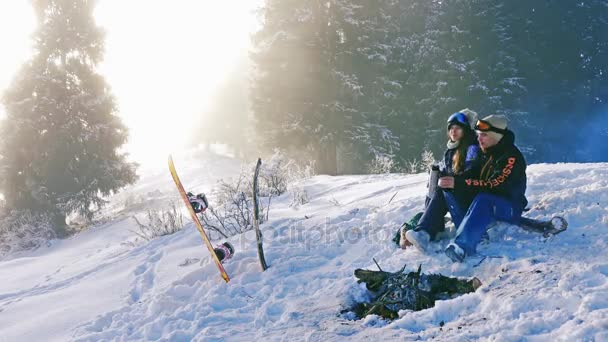 Timelapse av snowboardåkare par värma upp vid lägerelden utomhus, berg — Stockvideo