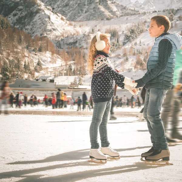 Happy children ice skating at rink outdoor