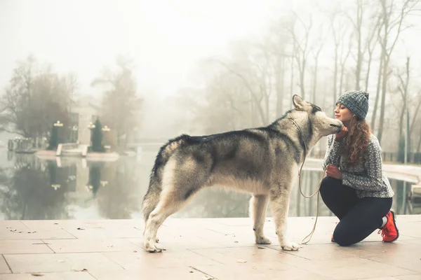 Imagen de una jovencita corriendo con su perro, Alaska Malamute — Foto de Stock