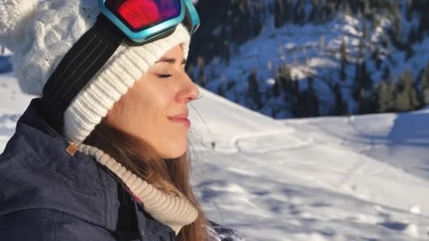 Portrait of beautiful young snowboarder woman looking at aerial view. — Stock Video