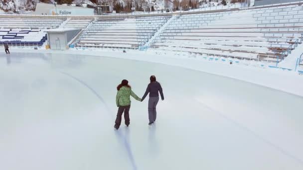 Vista aérea de patinação no gelo duas mulheres amigas ao ar livre, pista de gelo Medeo — Vídeo de Stock