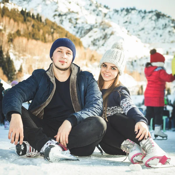 Vértes pár, a lány és a fiú korcsolyázás szabadtéri a jégpálya — Stock Fotó