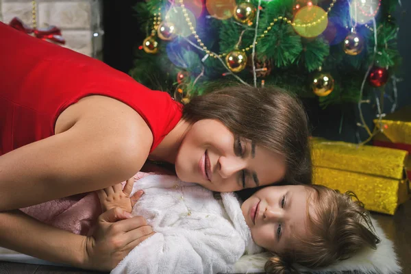 Söt baby och mamma dekorera en julgran. Röda bollar. — Stockfoto