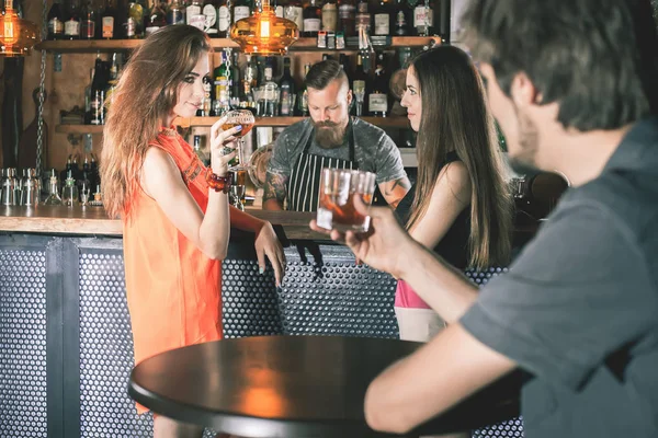 Drunk man sitting at bar, drinking cocktail, looking at girls