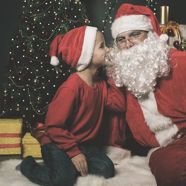 Papai Noel e menino perto da árvore de Natal decorada. Lista de desejos — Fotografia de Stock