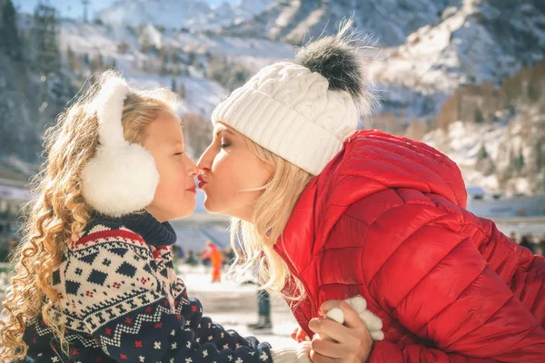 Mãe feliz e filha beijando ao ar livre, patinação no gelo — Fotografia de Stock