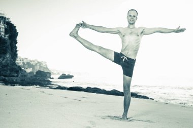 Cliff mavi deniz arka plan ile Yoga yapan yakışıklı erkek