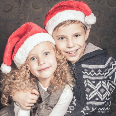 Komik çocuklar Noel ağacının yanında oturuyor. Santa şapka giymiş.