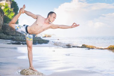 Cliff mavi deniz arka plan ile Yoga yapan yakışıklı erkek