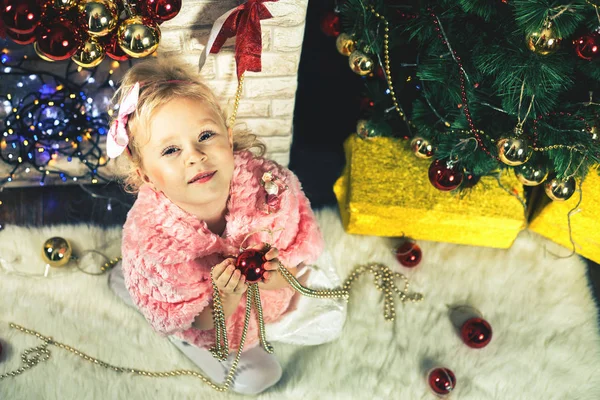 Engraçado menina abre caixa de presente de Natal perto da árvore de Natal — Fotografia de Stock