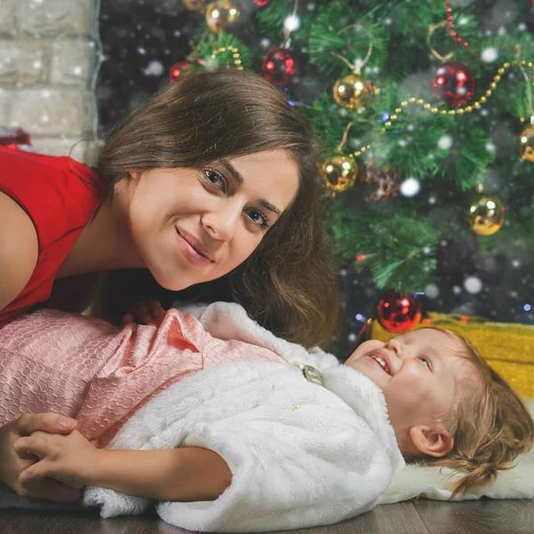 Söt baby och mamma dekorera en julgran. Röda bollar. — Stockfoto
