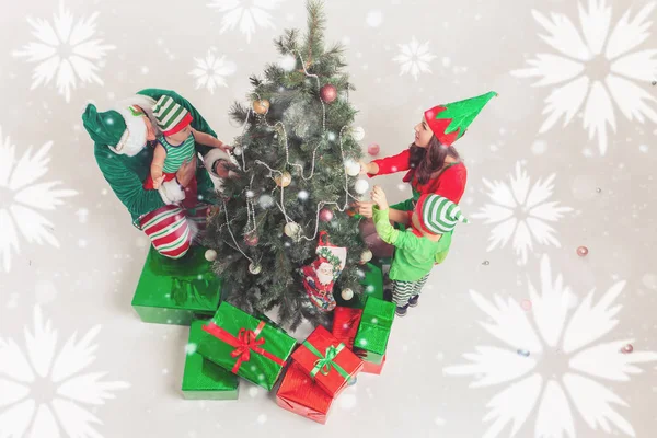 Happy family decorating Christmas tree, dressed in elf costumes — Stock Photo, Image
