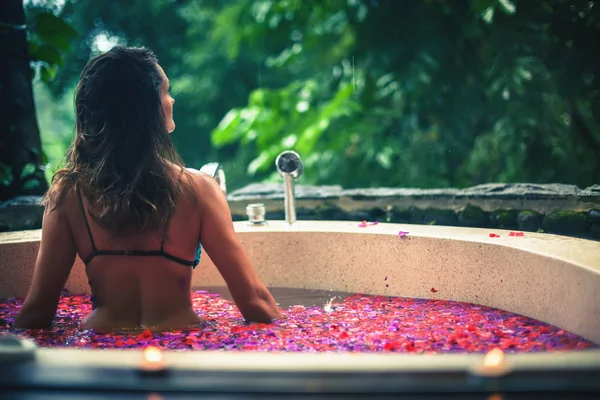 Donna rilassante bagno con fiori tropicali all'aperto in hotel di lusso — Foto Stock